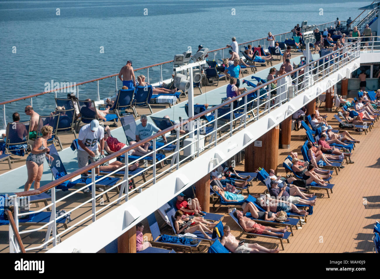 Les passagers à prendre le soleil sur la terrasse de la piscine d'un navire de croisière Banque D'Images