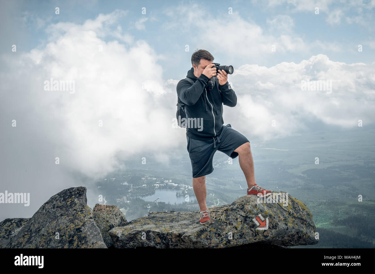Un photographe sur le haut d'une falaise abrupte et skyline en haute montagne. Banque D'Images