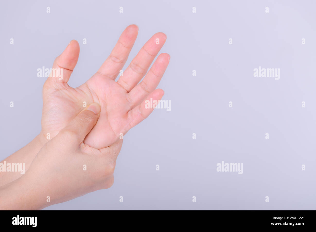 Femme souffrant de douleur à la main sur fond gris. Banque D'Images