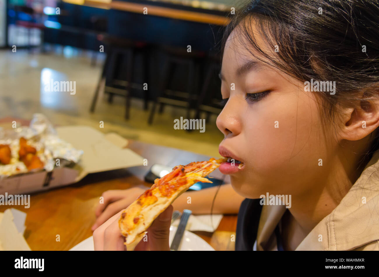 Belle asiatique boy eating pizza dans le restaurant. Banque D'Images