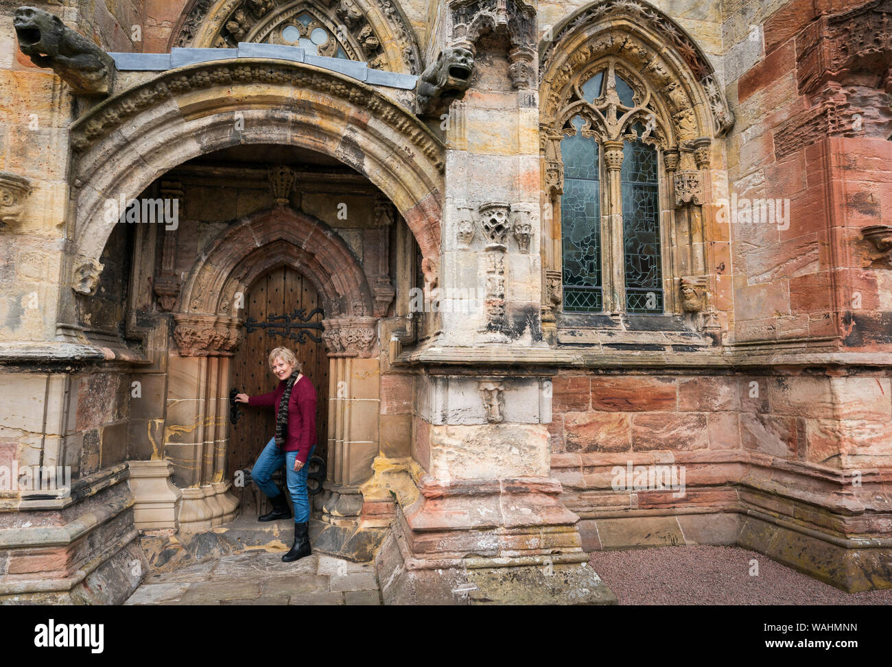 Femme de race blanche dans ses 50 ans se tient devant une porte de bois à la Chapelle de Rosslyn, Édimbourg, Écosse, Royaume-Uni, Europe Banque D'Images