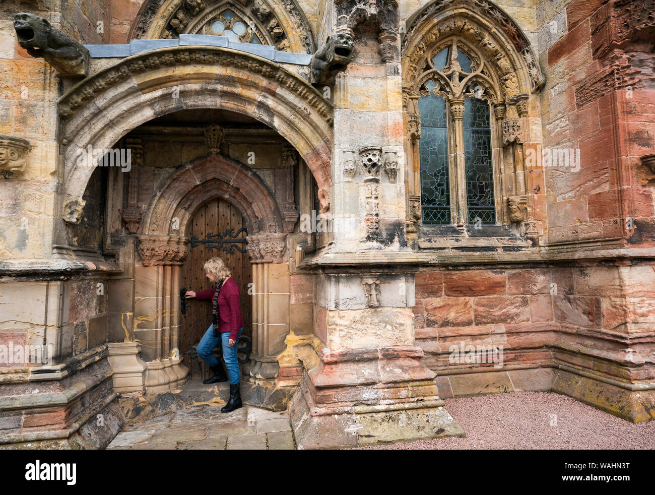 Femme de race blanche dans ses 50 ans ouvre une porte de bois à la Chapelle de Rosslyn, Édimbourg, Écosse, Royaume-Uni, Europe Banque D'Images