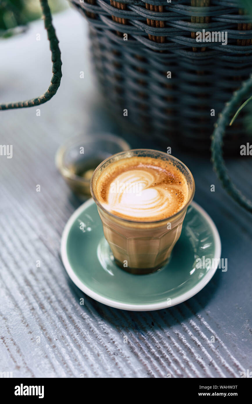 Tasse de café latte art avec soucoupe vert sur fond de bois Banque D'Images