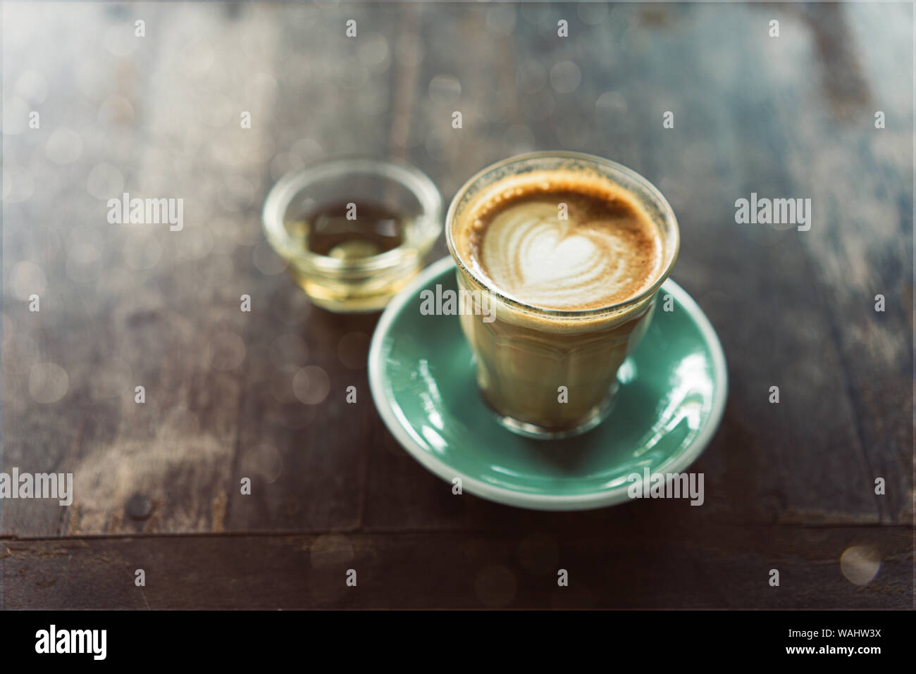 Tasse de café latte art avec soucoupe vert sur fond de bois Banque D'Images