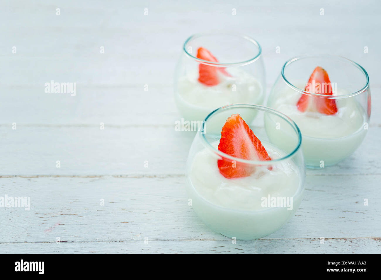 Saveur Original yaourt avec des fraises fraîches en verre clair sur fond de bois blanc Banque D'Images