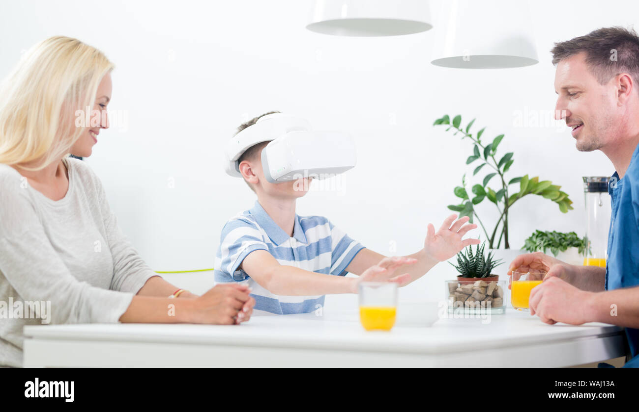Happy caucasian family à la maison à la table à manger, avoir l'amusement jouer des jeux à l'aide de casque de réalité virtuelle Banque D'Images
