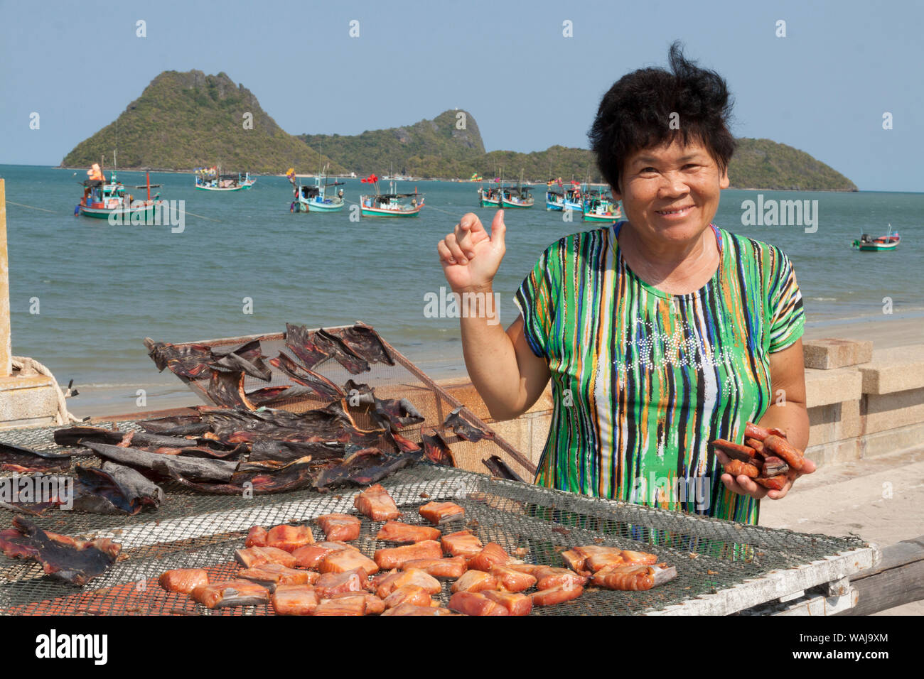 La Thaïlande, Prachuap Khiri Khan. Plage de Ao Manao. Smiling woman Cuisiner les poissons sur la plage. Banque D'Images