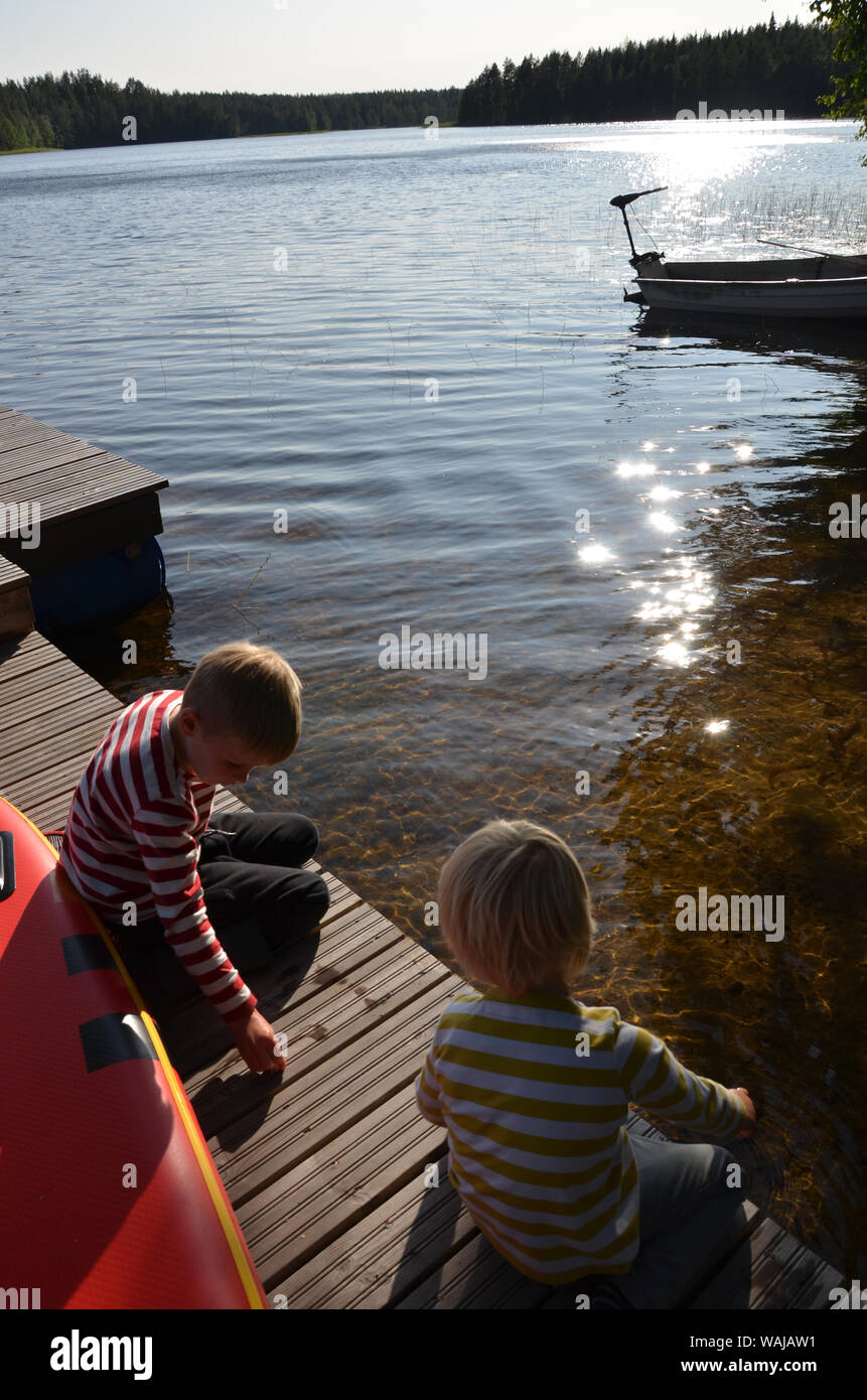 Deux petits garçons blonds, les frères jouant sur le lac, jetée par Sarkjarvi la Finlande. Banque D'Images