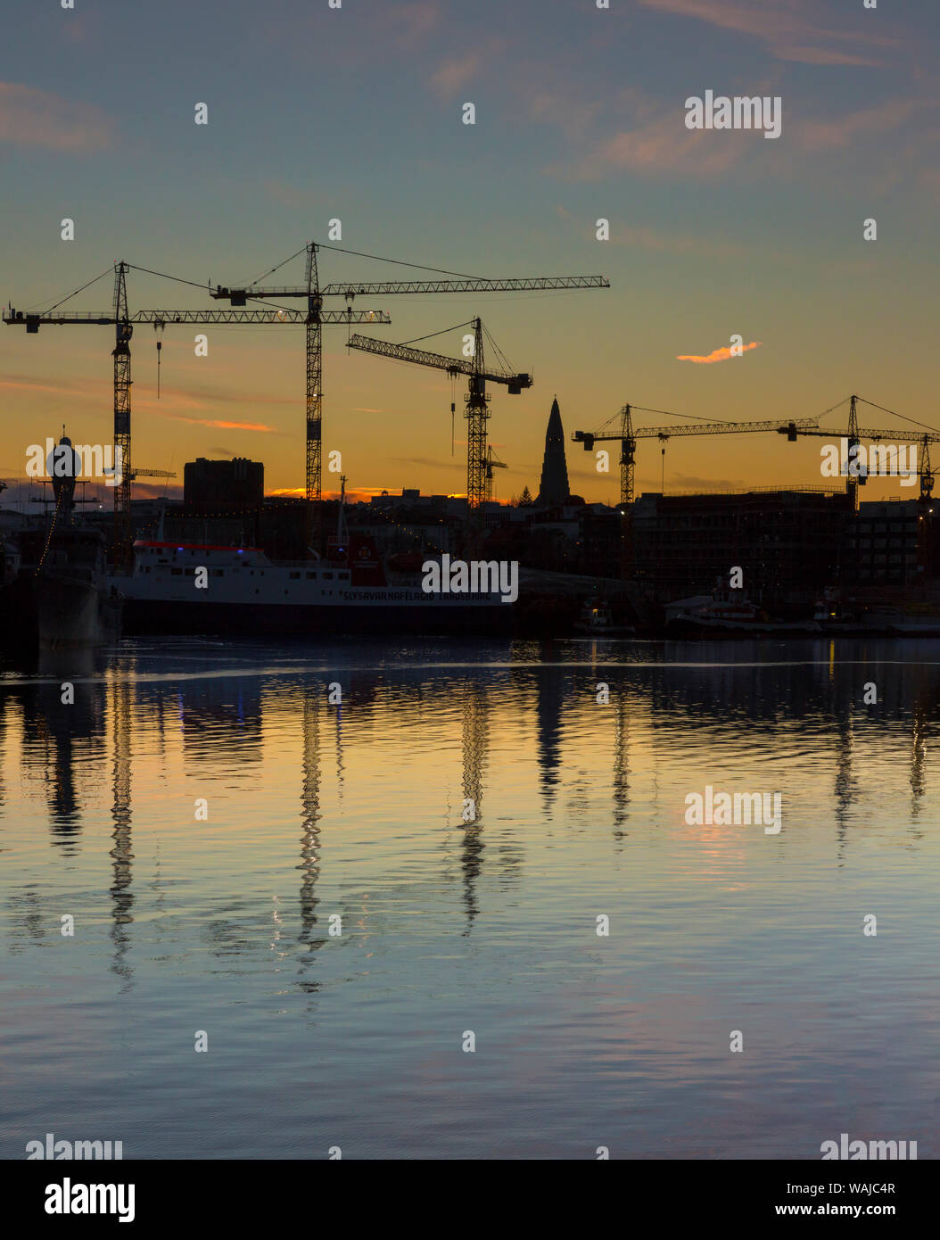 L'Islande, Reykjavik, le vieux port. Clocher de l'église Hallgrimskirkja et silhouettes de grues au lever du soleil. En tant que crédit : Wendy Kaveney Jaynes / Galerie / DanitaDelimont.com Banque D'Images