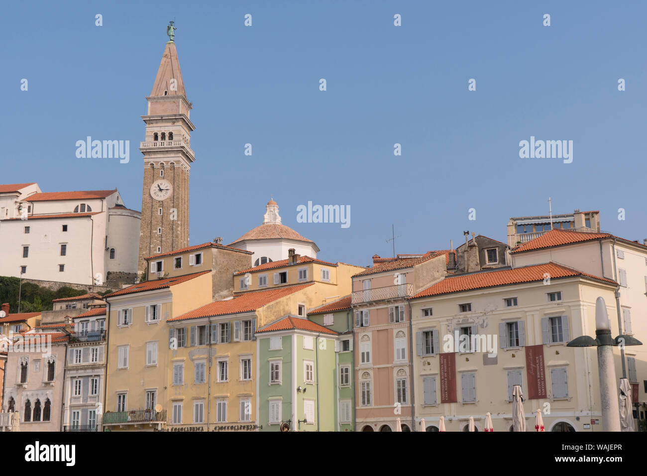 La Slovénie, Piran. Les bâtiments aux teintes pastel autour Tartinia Plaza s'asseoir sous l'église paroissiale de Saint Georges sur la colline. Banque D'Images