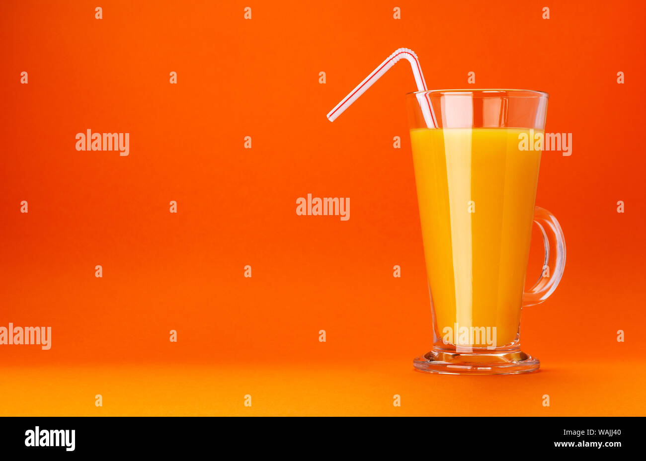 Verre de jus d'orange isolé sur fond orange couleur avec copie espace pour le texte Banque D'Images