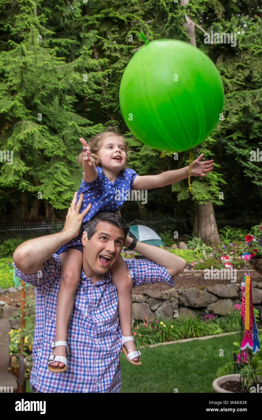 Issaquah, Washington State, USA. Trente-quatre ans, père tenant sa fille de trois ans alors qu'elle attrape un ballon lancé à elle. (Monsieur,PR) Banque D'Images