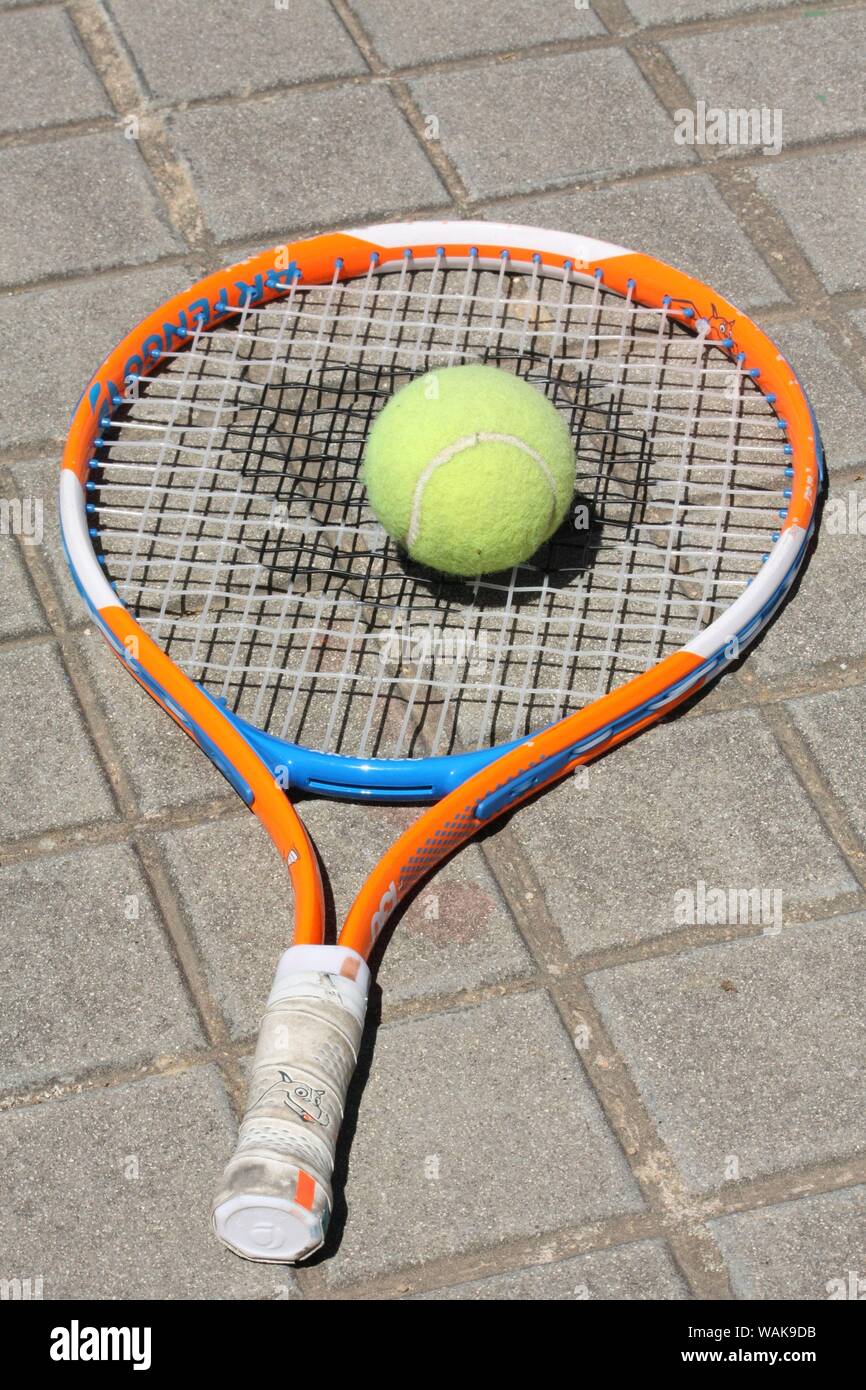 Raquette et balle de tennis abandonnés sur le trottoir. Banque D'Images