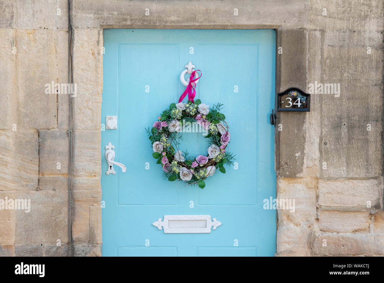 En bois bleu clair de la porte du chalet avec une couronne de fleurs en soie et ruban rose. Winchcombe, Cotswolds, Gloucestershire, Angleterre Banque D'Images