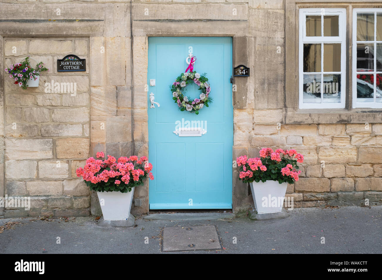 En bois bleu clair de la porte du chalet avec une couronne de fleurs en soie et ruban rose. Winchcombe, Cotswolds, Gloucestershire, Angleterre Banque D'Images
