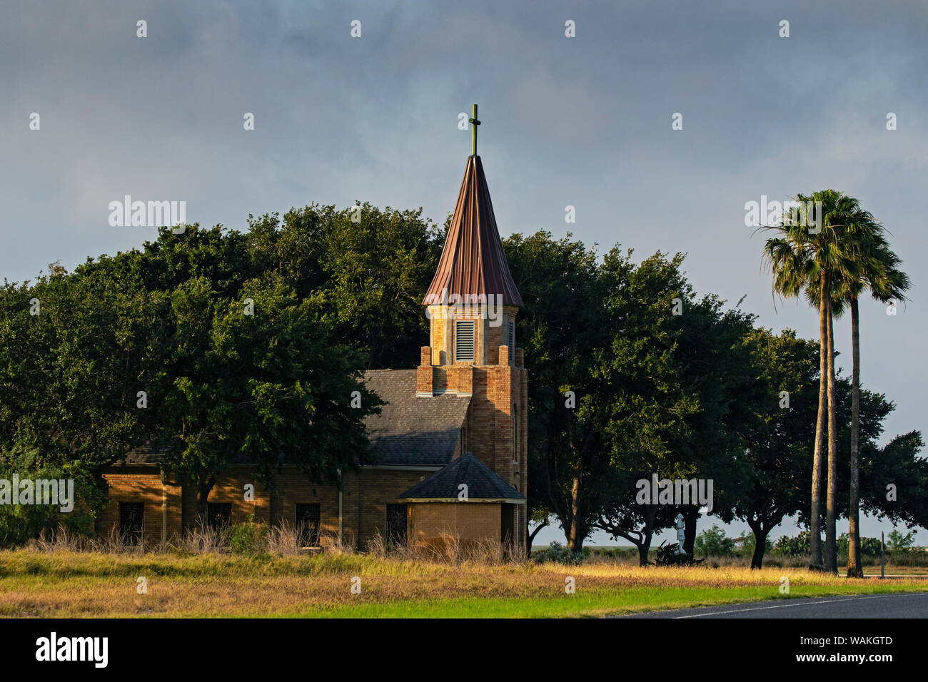 Église catholique dans l'ombre d'un bosquet d'arbres. Banque D'Images