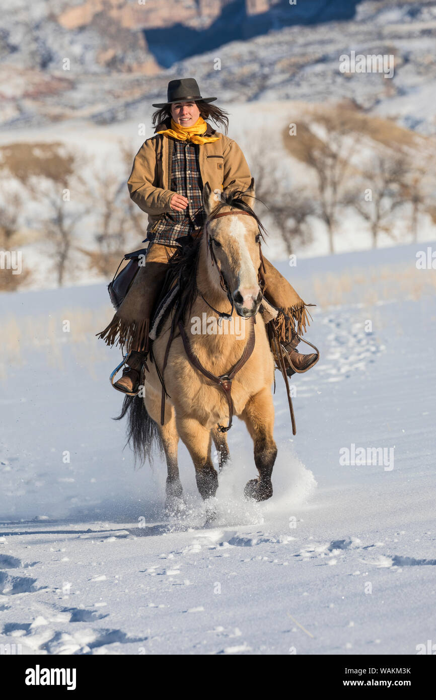 Cheval de cow-boy dur sur Hideout Ranch, Shell, Wyoming. Cowgirl équitation dans la neige. (MR) Banque D'Images