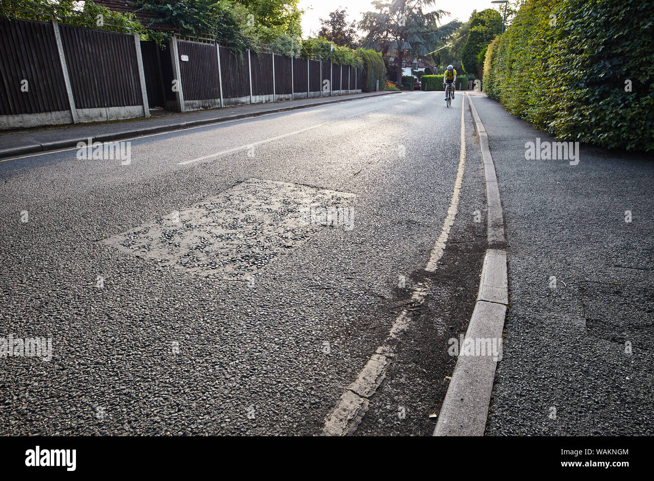 Bas vers le bas sur une route tranquille en Angleterre avec un cycliste qui apparaissent au loin. Banque D'Images