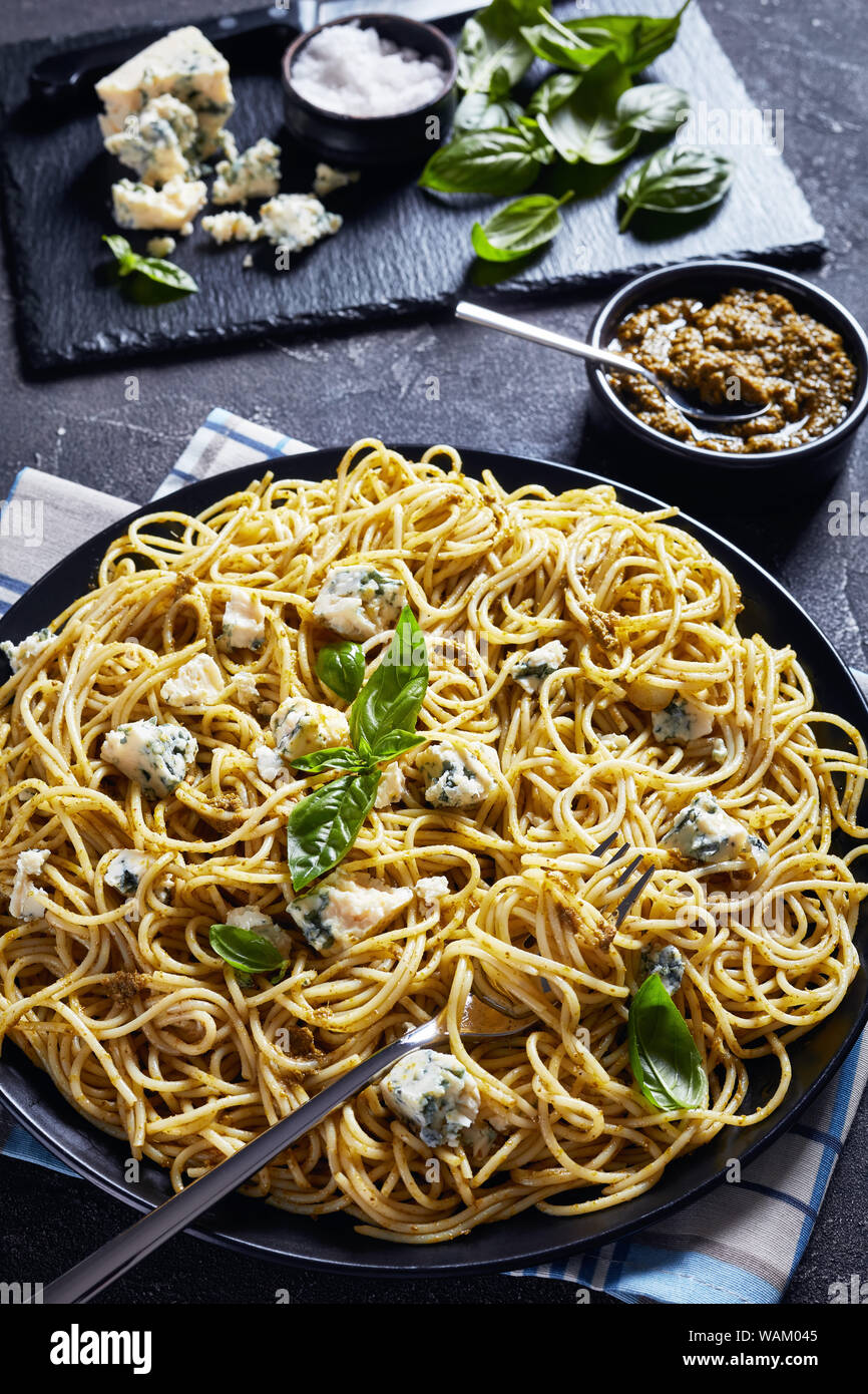 Délicieux spaghetti au pesto de basilic et de fromage bleu sur une plaque noire sur une table avec le pesto dans un bol noir et ingrédients sur une ardoise Cuttin ' Banque D'Images