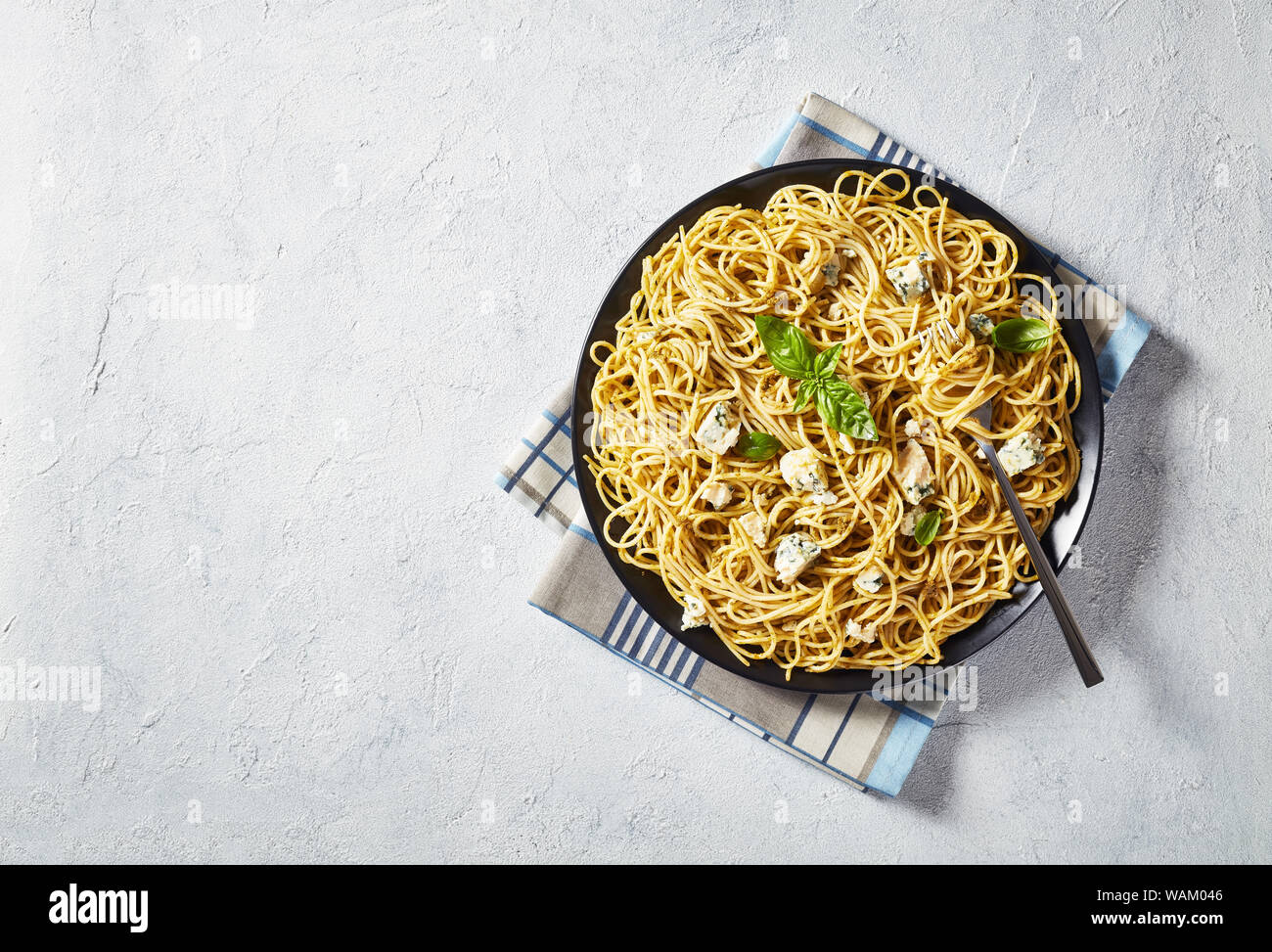 Vue de dessus de spaghetti au pesto de basilic genovese et le fromage bleu sur une plaque noire sur une table en béton blanc, vue de dessus, flatlay, close-up Banque D'Images