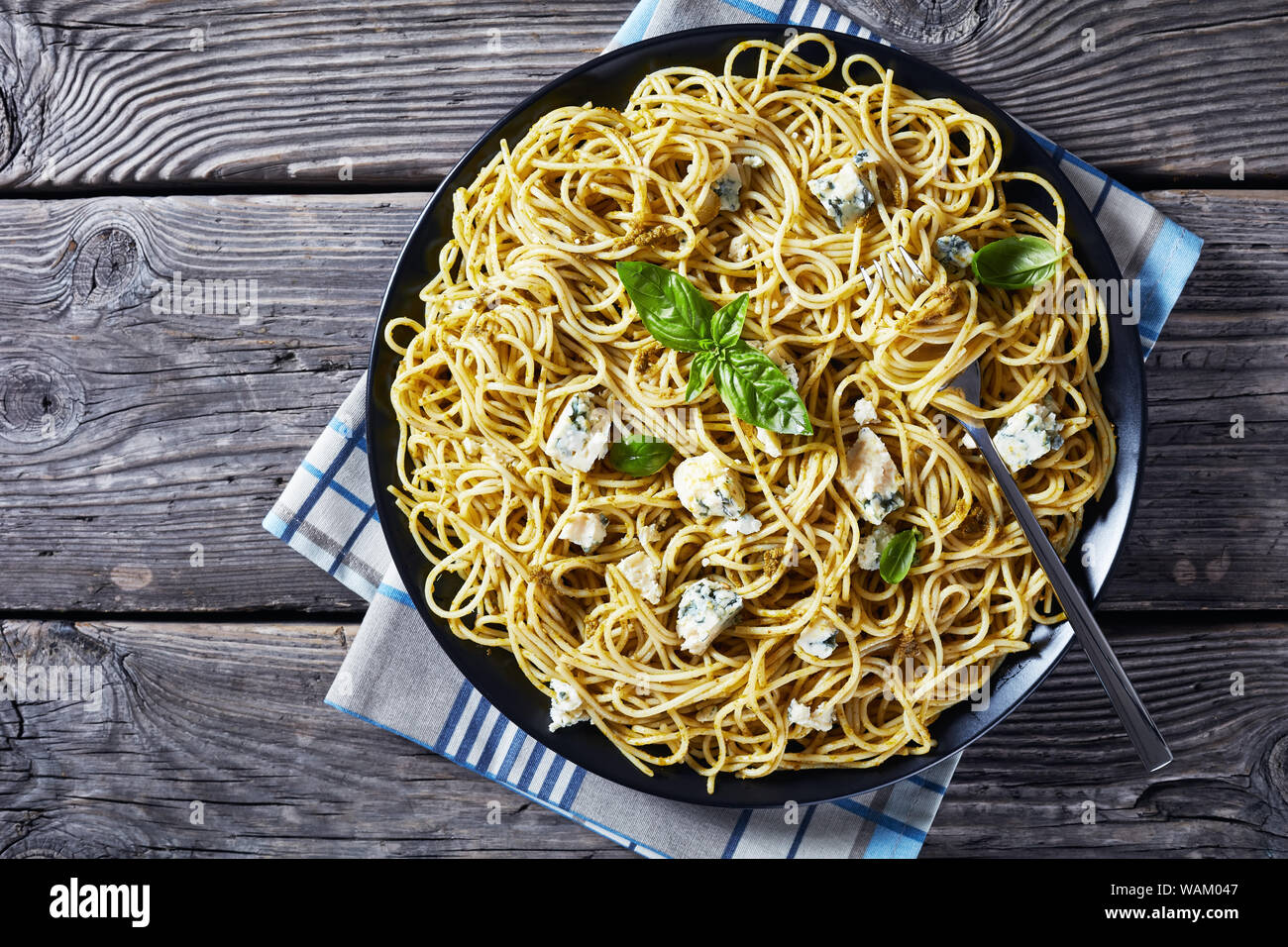 Vue de dessus de spaghetti au pesto de basilic genovese et le fromage bleu sur une plaque noire sur une table en béton avec des ingrédients sur une plaque en ardoise, vue à partir de Banque D'Images
