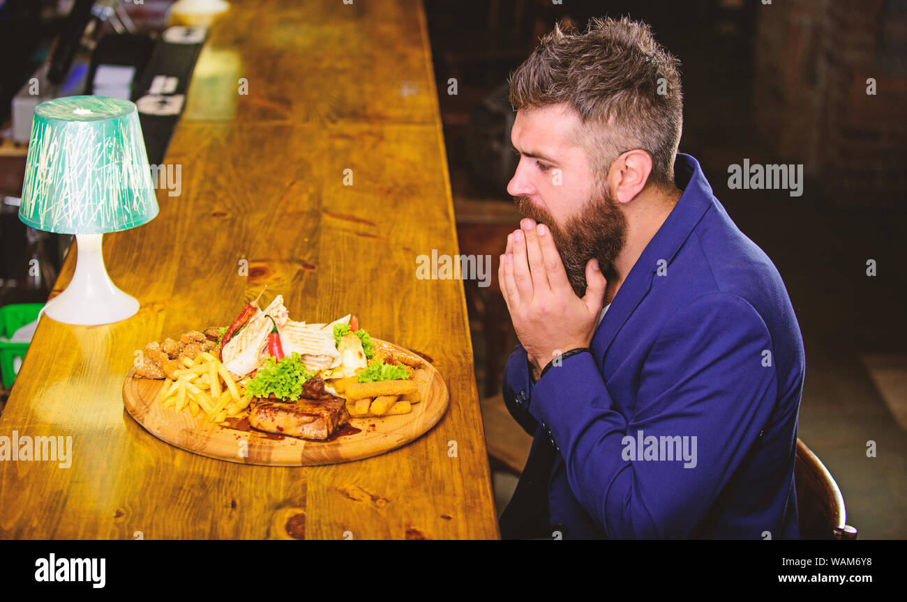 Profitez de repas. Il méritent de délicieux repas. Des calories. Vous pourrez vous détendre après une dure journée de travail. Woman costume formel s'asseoir à comptoir bar. L'homme a reçu de pommes de terre frites repas avec viande et poisson, lavash. Banque D'Images