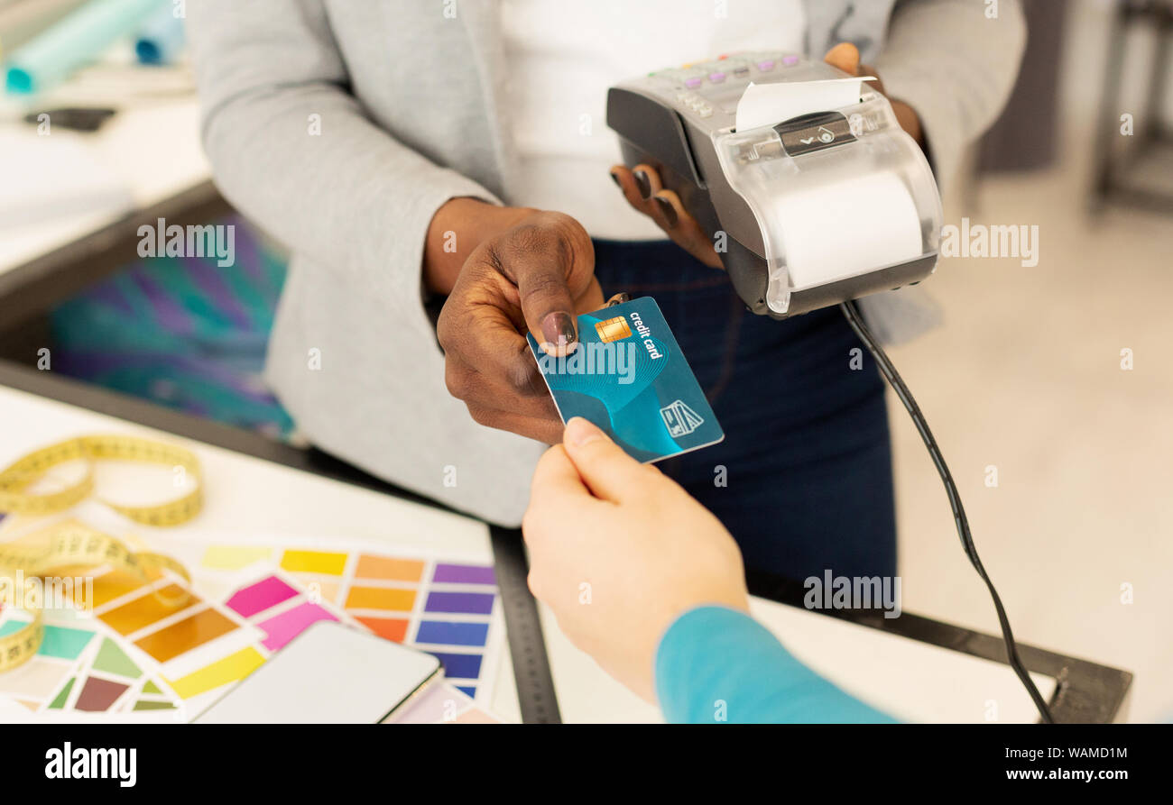 Femme shop assistant effectue le paiement par carte de crédit pour des vêtements Banque D'Images