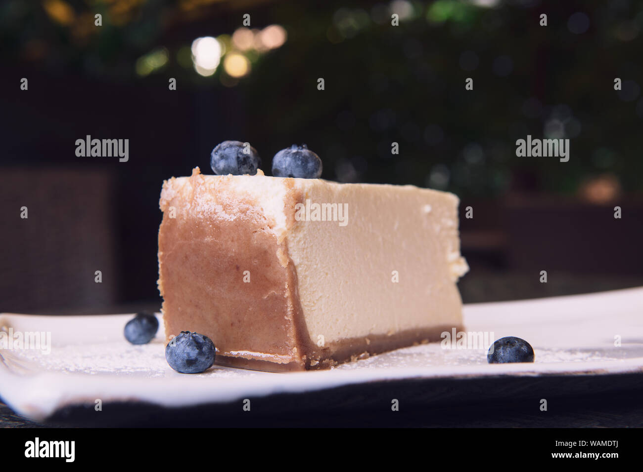 New York cheesecake avec les bleuets. Une tranche d'un gâteau savoureux avec une croûte brune. Bokeh avec gros plan et l'espace de copie. Banque D'Images