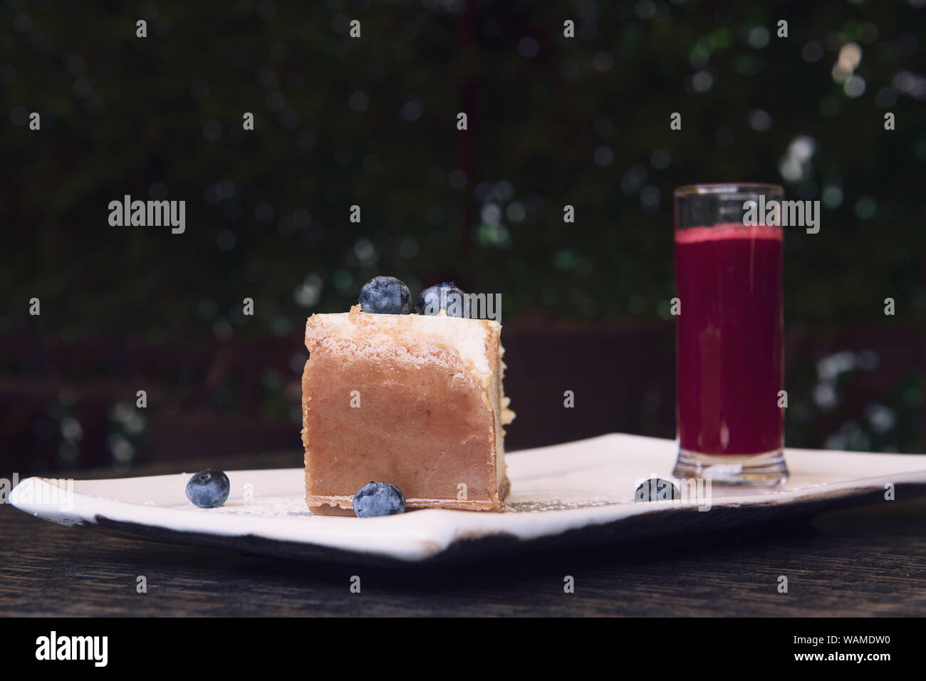 New York cheesecake avec les bleuets. Une tranche d'un gâteau savoureux avec une croûte brune. Servi avec un verre de sauce aux framboises. Bokeh avec gros plan et copie spa Banque D'Images