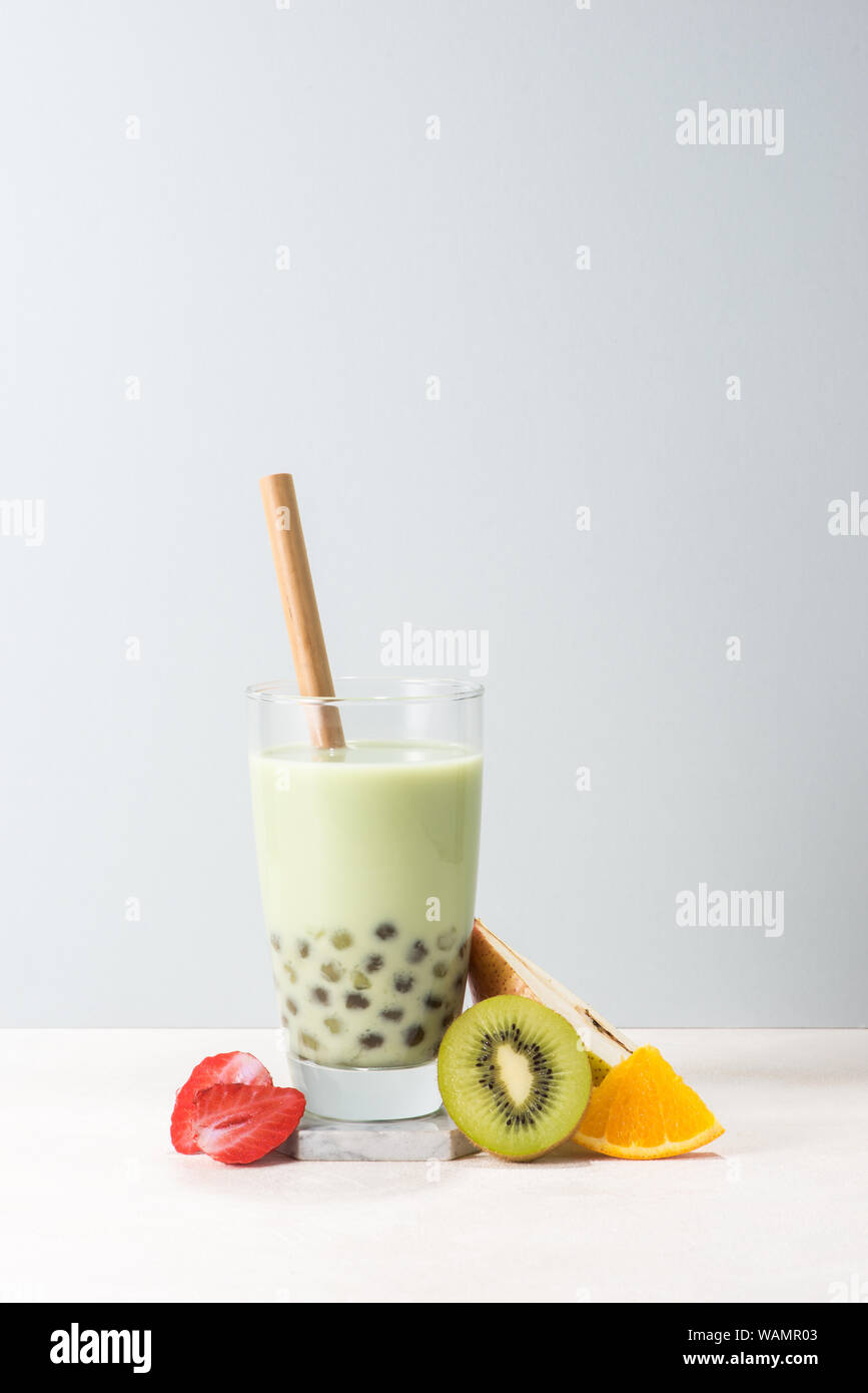 Boba/ buble plateau verre avec kiwi, fraise, des tranches d'orange sur fond bleu. Banque D'Images