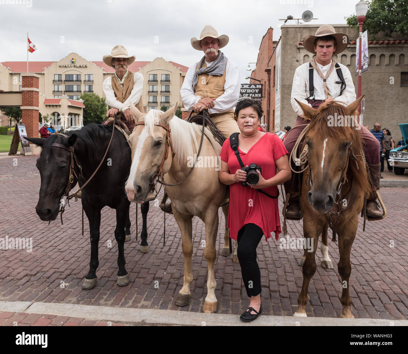 Cowpokes Maltby, Mike Mangold, David Hopper Lane, de gauche à droite à cheval, qui aide Texas Longhorn des troupeaux bovins pendant une promenade deux fois par jour (par opposition à toute exécution des taureaux) dans le quartier Station Stockyards de Fort Worth, Texas, inscrivez-vous Lola, le Lavender-Hardisty Stockyards' photographe officiel, pour une photo Banque D'Images