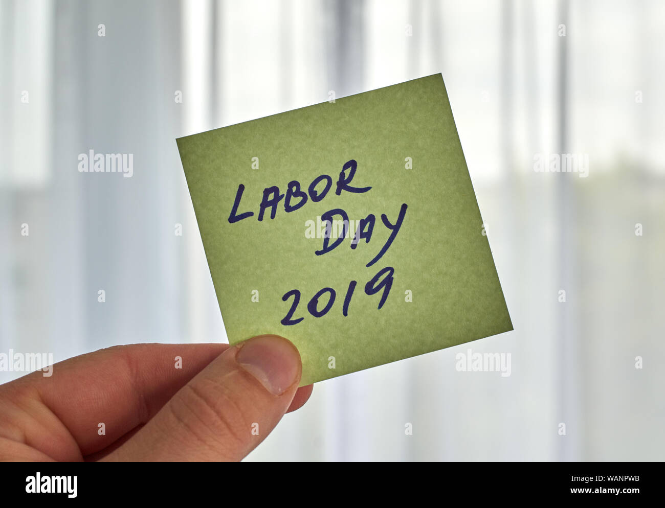 Une main qui tient la fête du Travail écrit écrit sur un post-it Banque D'Images
