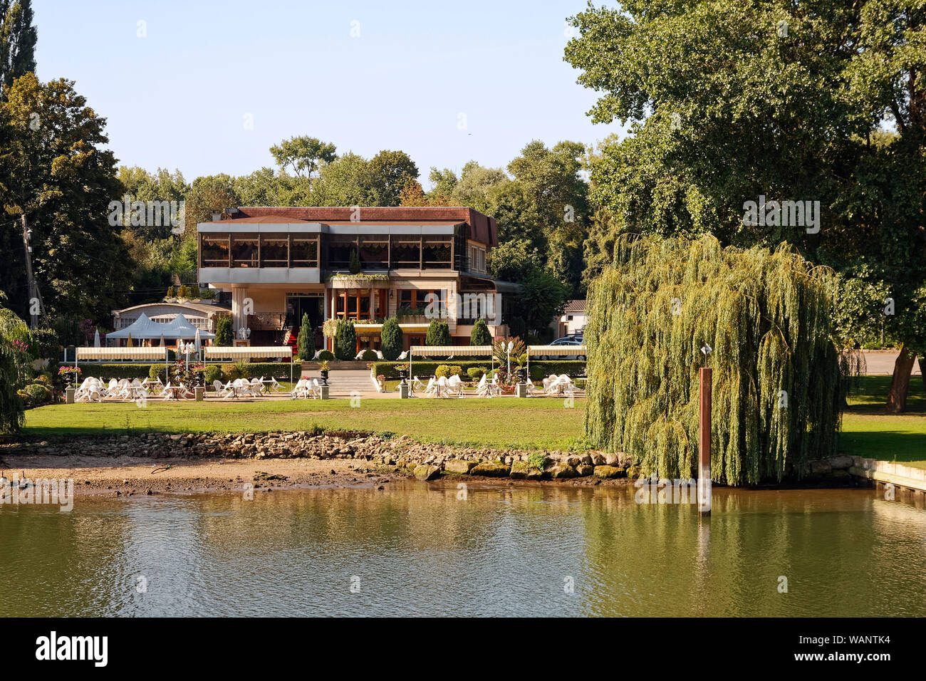 Scène de la rivière Seine, petit hôtel, restaurant, de grandes fenêtres, patio, tables, chaises, tentes, du gazon, des arbustes, arbres, attrayant, Europe ; Normandie ; Fr Banque D'Images