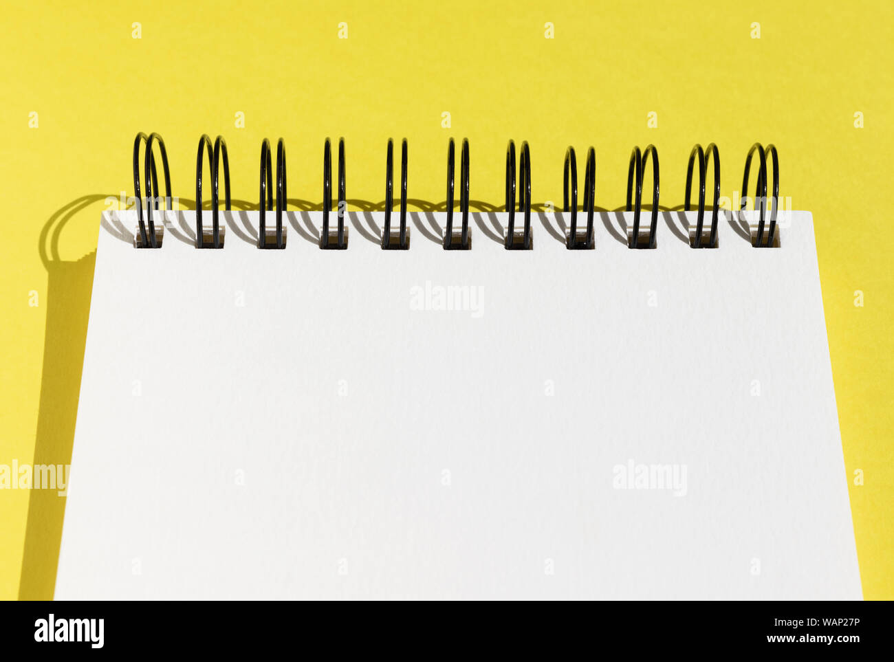 Haut d'un bloc-notes à spirale en blanc sur fond jaune, avec une page blanche et copy space Banque D'Images