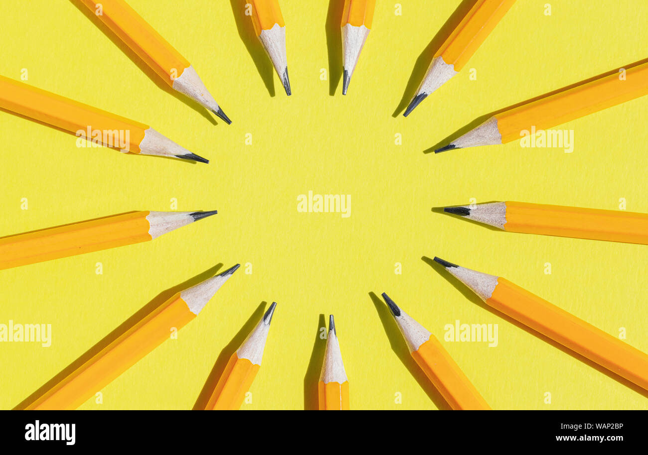 Cercle des crayons de couleur orange sur fond jaune, avec copie espace au milieu Banque D'Images