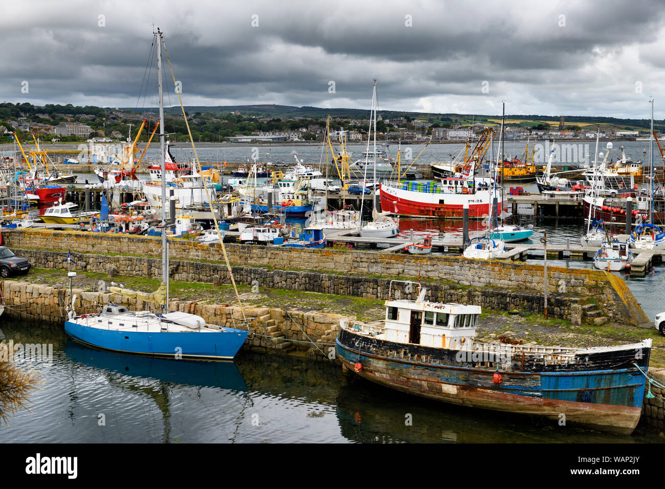 Avis de divers bateaux amarrés au port de Newlyn piles en pierres avec vue sur l'ensemble de Penzance Cornwall Angleterre Mounts Bay Banque D'Images