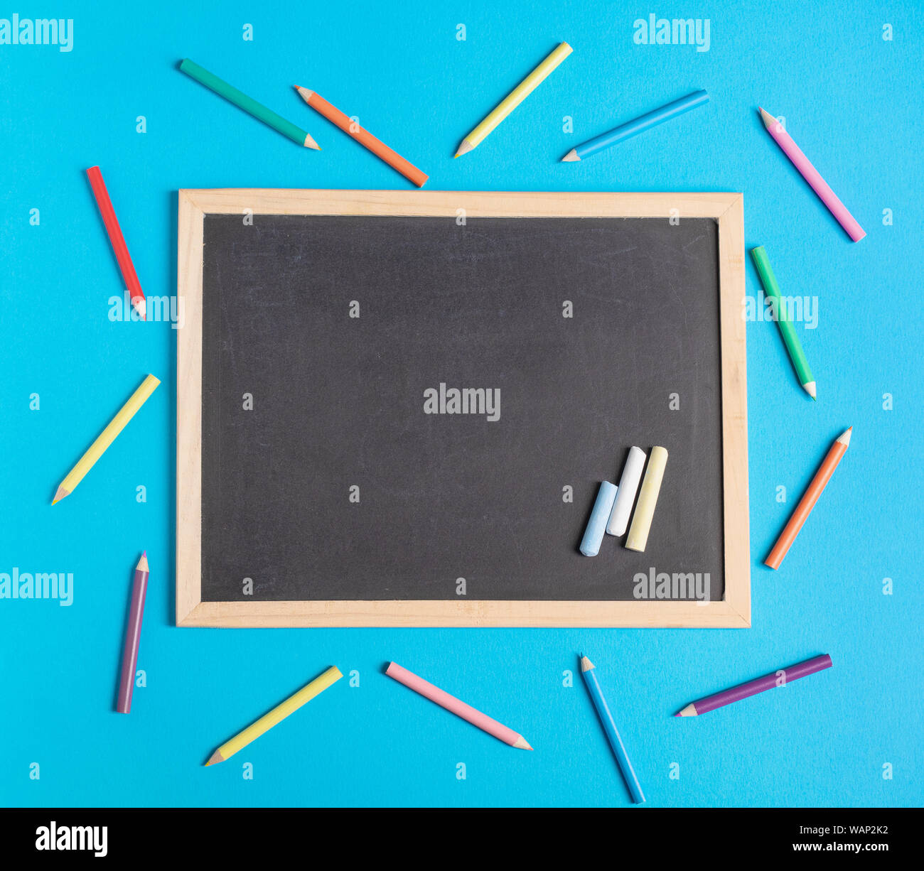 Blank chalkboard et crayons de couleur sur un fond bleu. Retour à l'école télévision concept laïcs Banque D'Images
