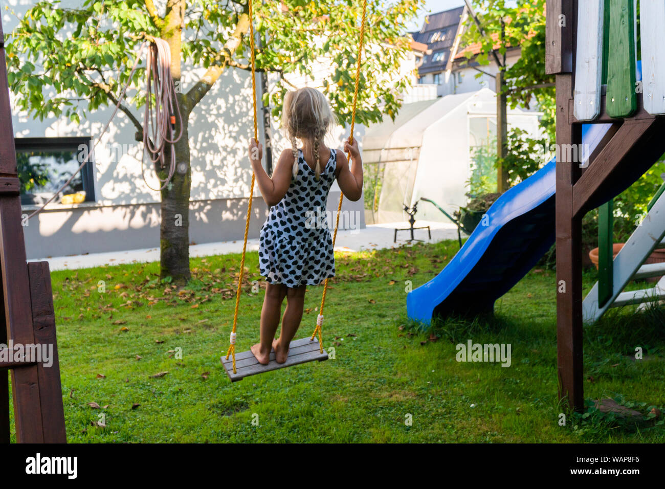 3-5 ans fille blonde s'amusant sur une balançoire à l'extérieur. Jeux d'été. Fille se balançant de haut. Jeune enfant sur la balançoire dans le jardin Banque D'Images