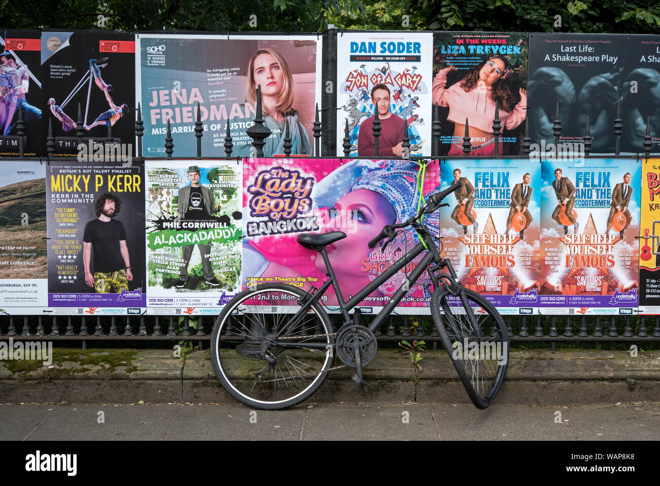 A broken bicycle leaning against railing couverts à Edinburgh Fringe Festival d'affiches. Banque D'Images