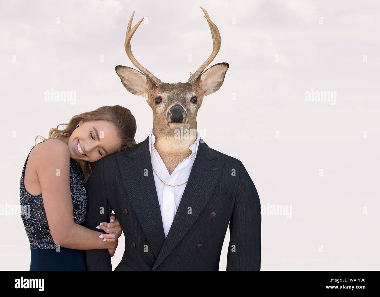 Smiling teenage girl with big buck deer in tuxedo costume isolé sur fond rose blush doux Banque D'Images