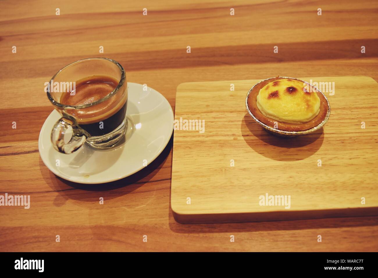 Tarte au fromage blanc sur plateau en bois et Café espresso en verre transparent sur table marron Banque D'Images