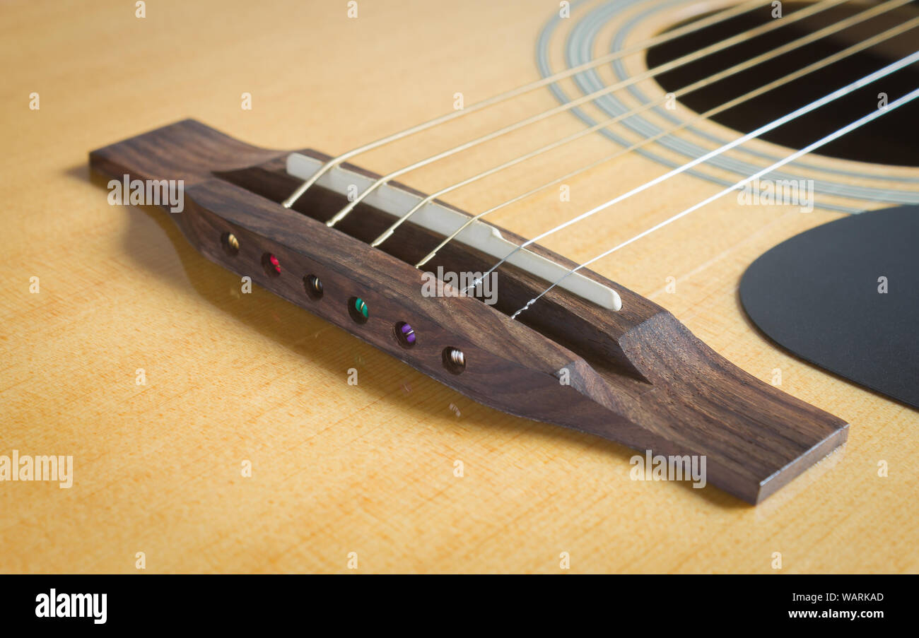 Pont de bois et de selle et son trou avec Pickguard et corde de guitare  acoustique en lumière naturelle Photo Stock - Alamy