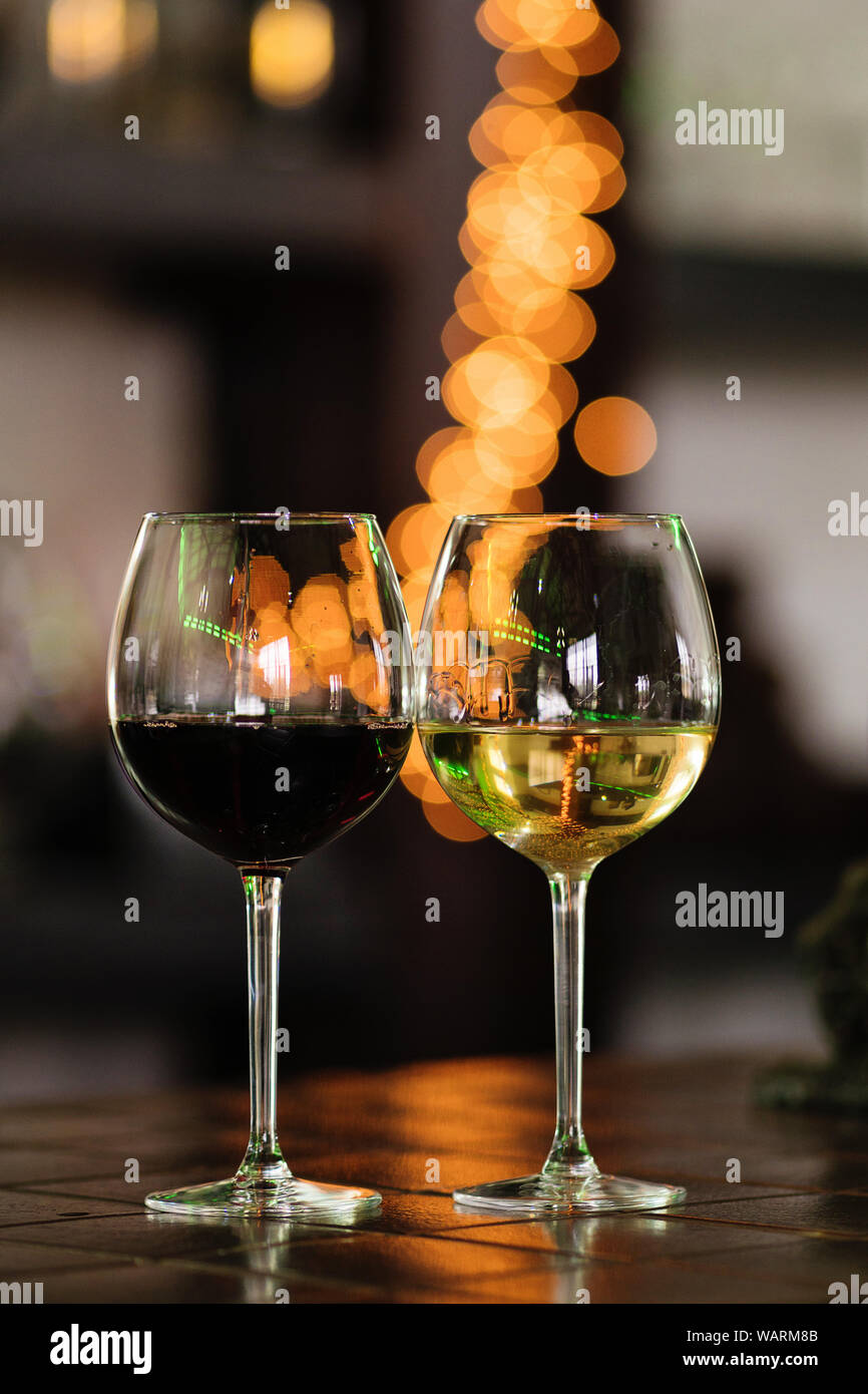 Deux verres de vin blanc et rouge debout sur une table. Bokeh coloré. Dégustations de vin, wine tour. La tonalité chaude. Concept des boissons alcoolisées. Banque D'Images