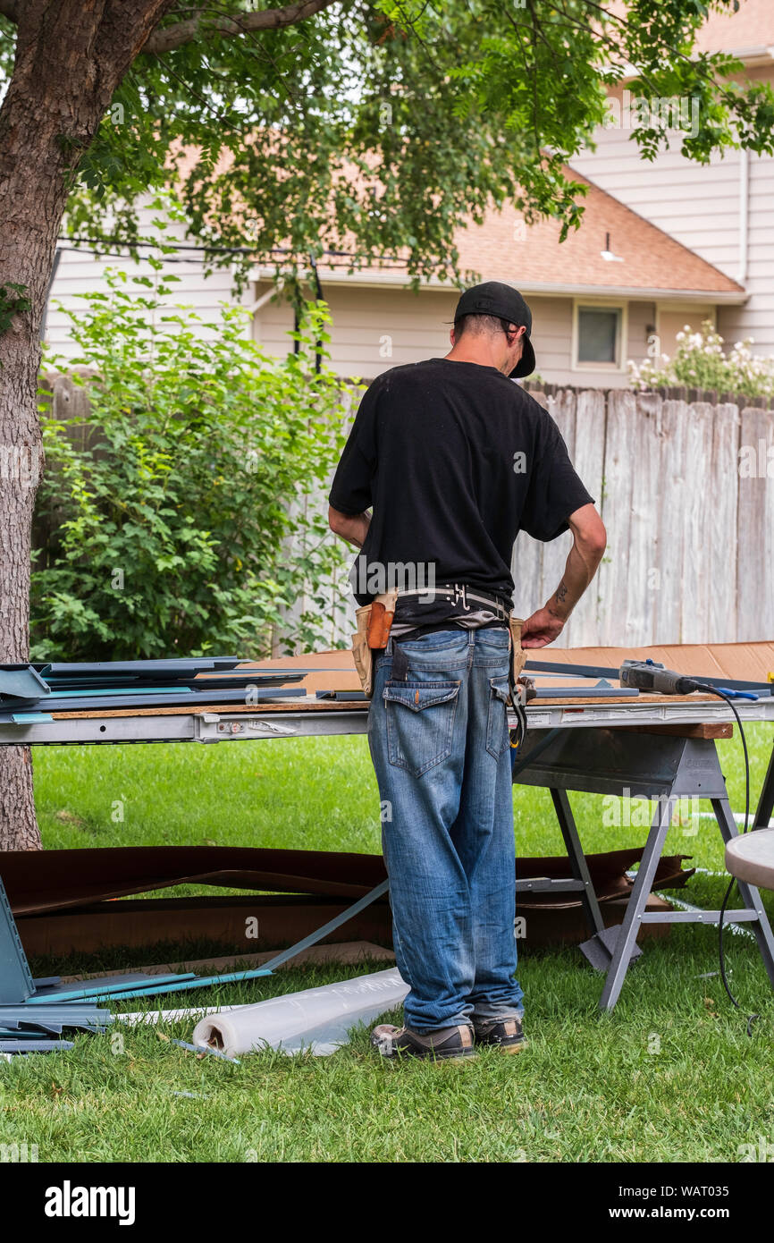 Mesures et découpes un ouvrier de revêtement de vinyle pour l'installation sur une maison. USA. Banque D'Images