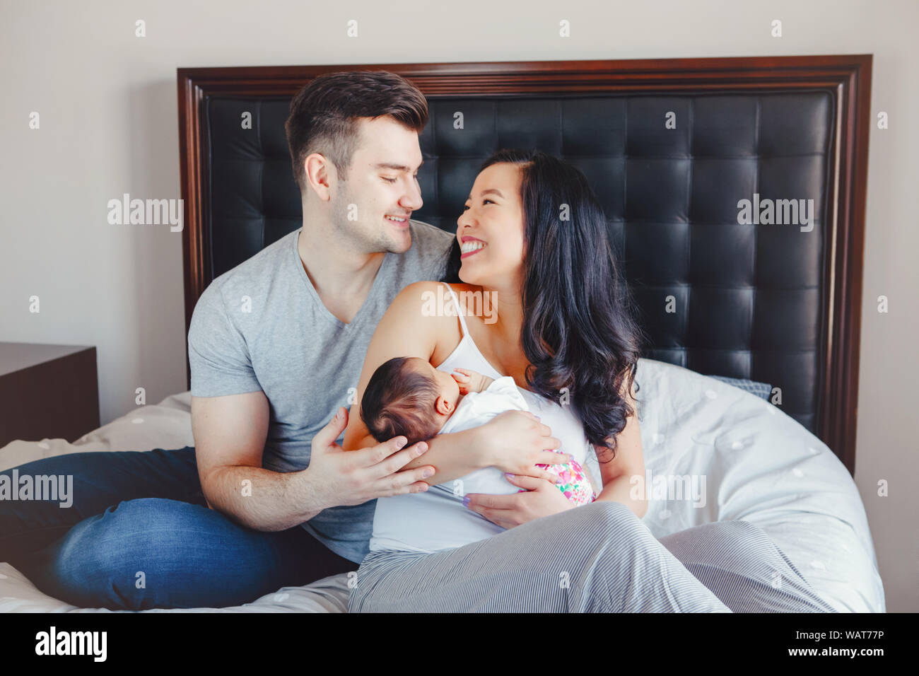 Portrait of beautiful smiling Chinese Asian mother and Caucasian father with mixed race nouveau-né bébé fille. Famille heureuse dans la chambre. Cdm Banque D'Images