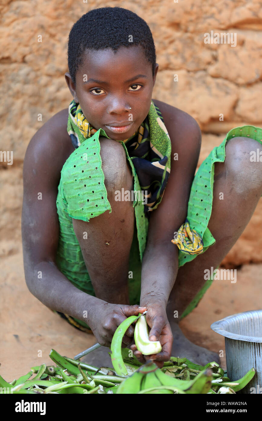 Une jeune femme épluche des plantains en cuisinant dans un village près de Kigoma, en Tanzanie Banque D'Images