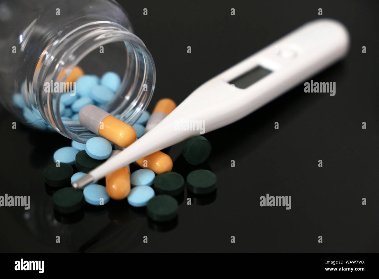 Comprimés dans une bouteille, des médicaments dans des capsules et un thermomètre digital sur une table en verre. Concept de pharmacie, antipirético, traitement de la fièvre Banque D'Images