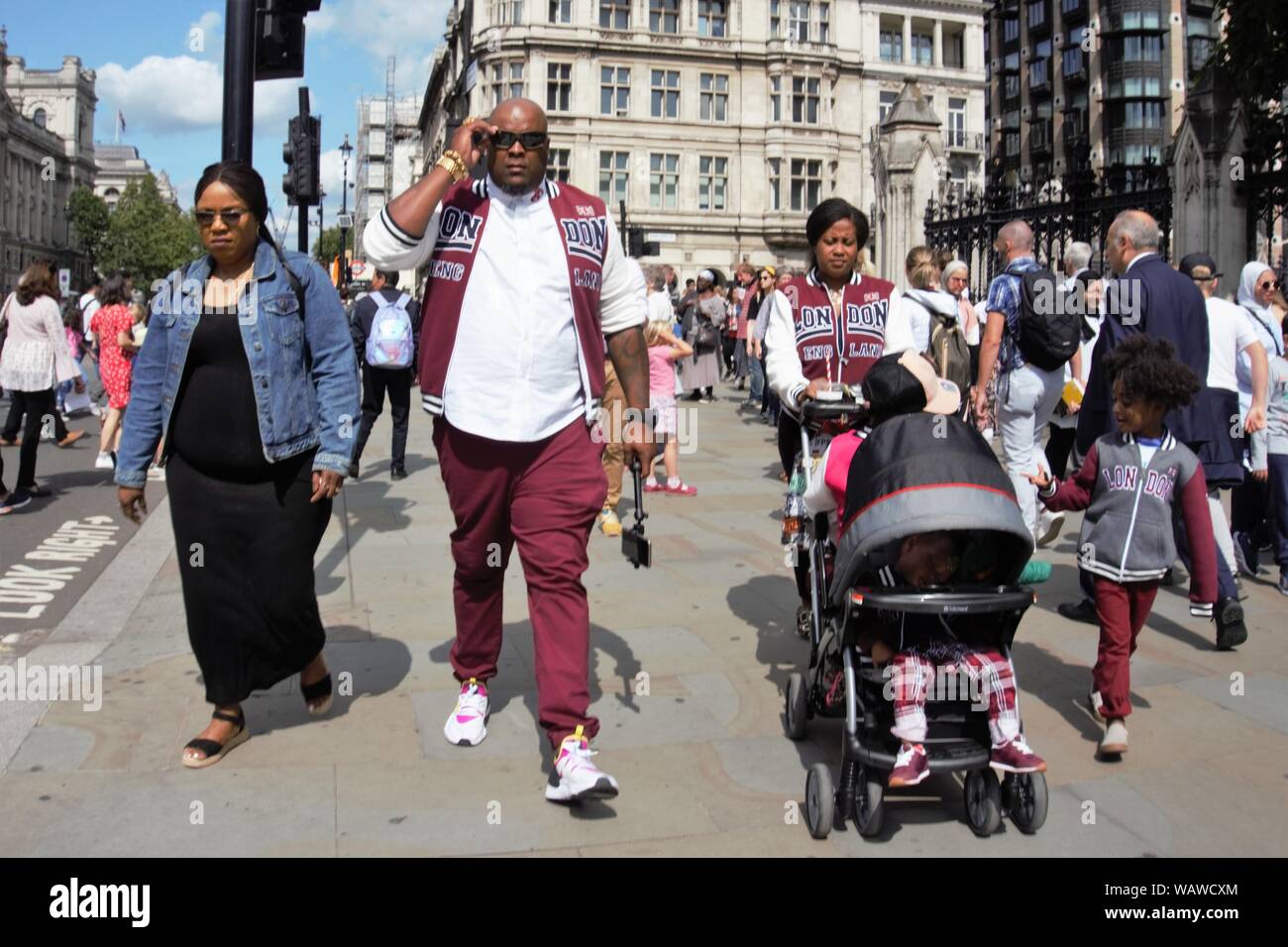 Une famille noire, une femme poussant un landau, flâner le long de la place du Parlement, Westminster, London, UK Banque D'Images