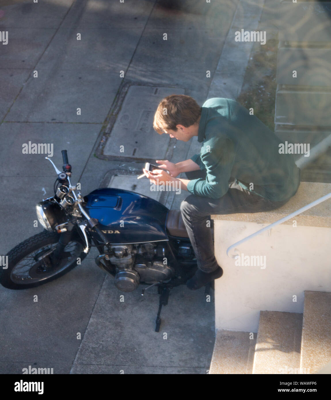 San Francisco, CA - 21 mai 2016 : Un homme fume une cigarette tout en regardant son iPhone à San Francisco. Banque D'Images