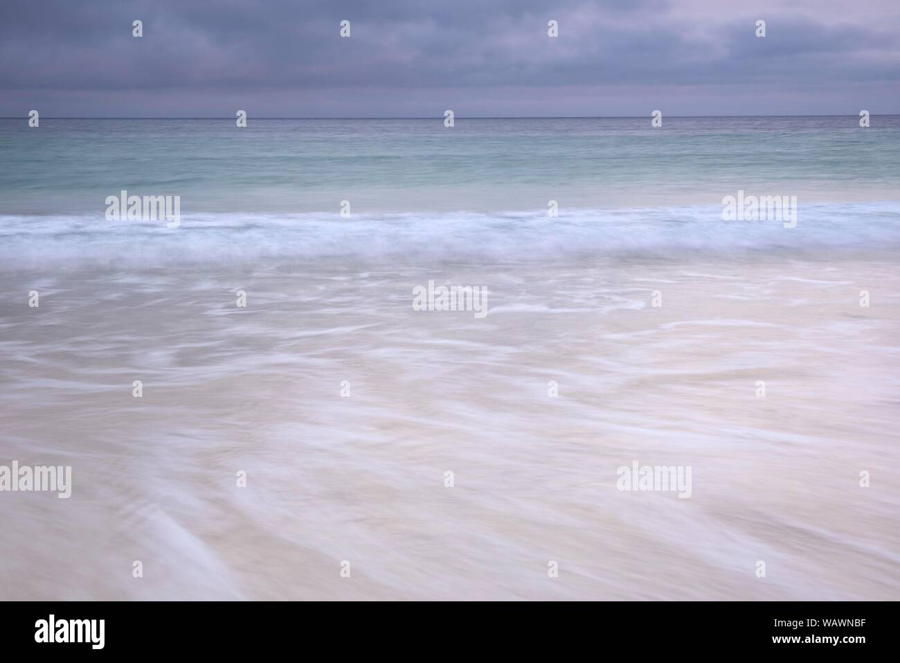 Et les vagues de pulvérisation fonctionnant sur une plage de sable fin, sombre de nuages de pluie sur l'océan Atlantique, Isle of Harris, Scotland, United Kingdom Banque D'Images